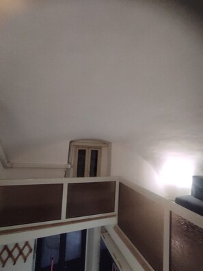 Una habitación con techo inclinado, una ventana con marco de madera y un panel decorativo en la pared.