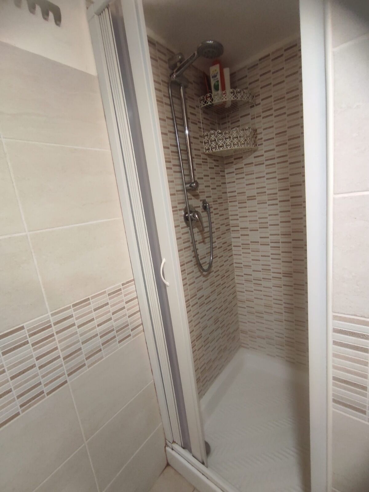 A shower area with a glass door, tiled walls, and a showerhead.