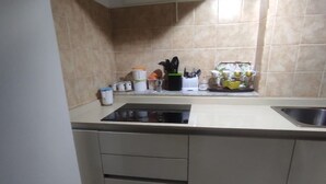Una cocina con estufa, lavamanos, armarios y salpicadero de azulejos.