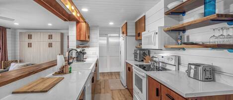A modern kitchen with white cabinetry, wooden accents, and built-in appliances.