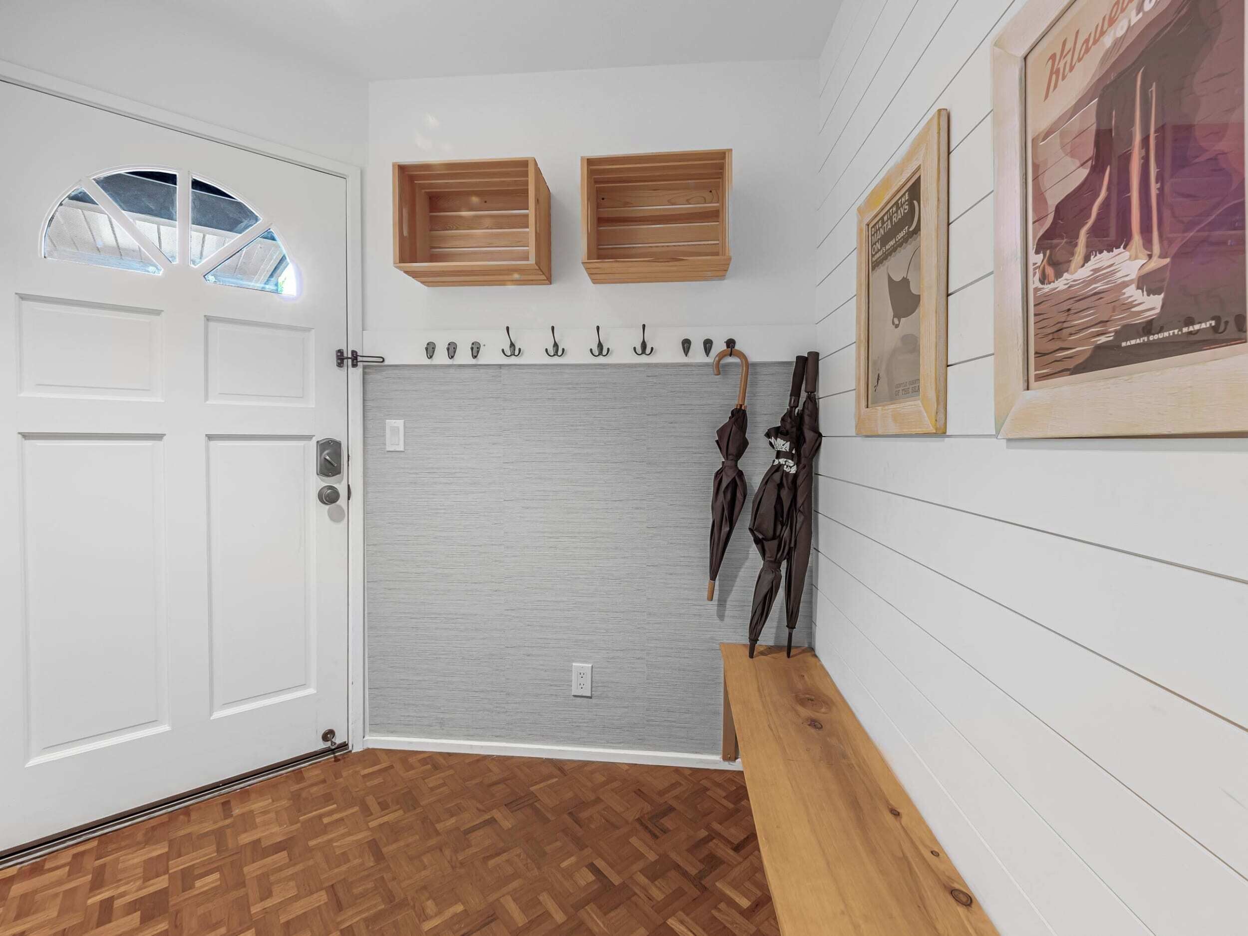 A room with a white door, a grey sliding door, wooden benches, and wall-mounted hooks.