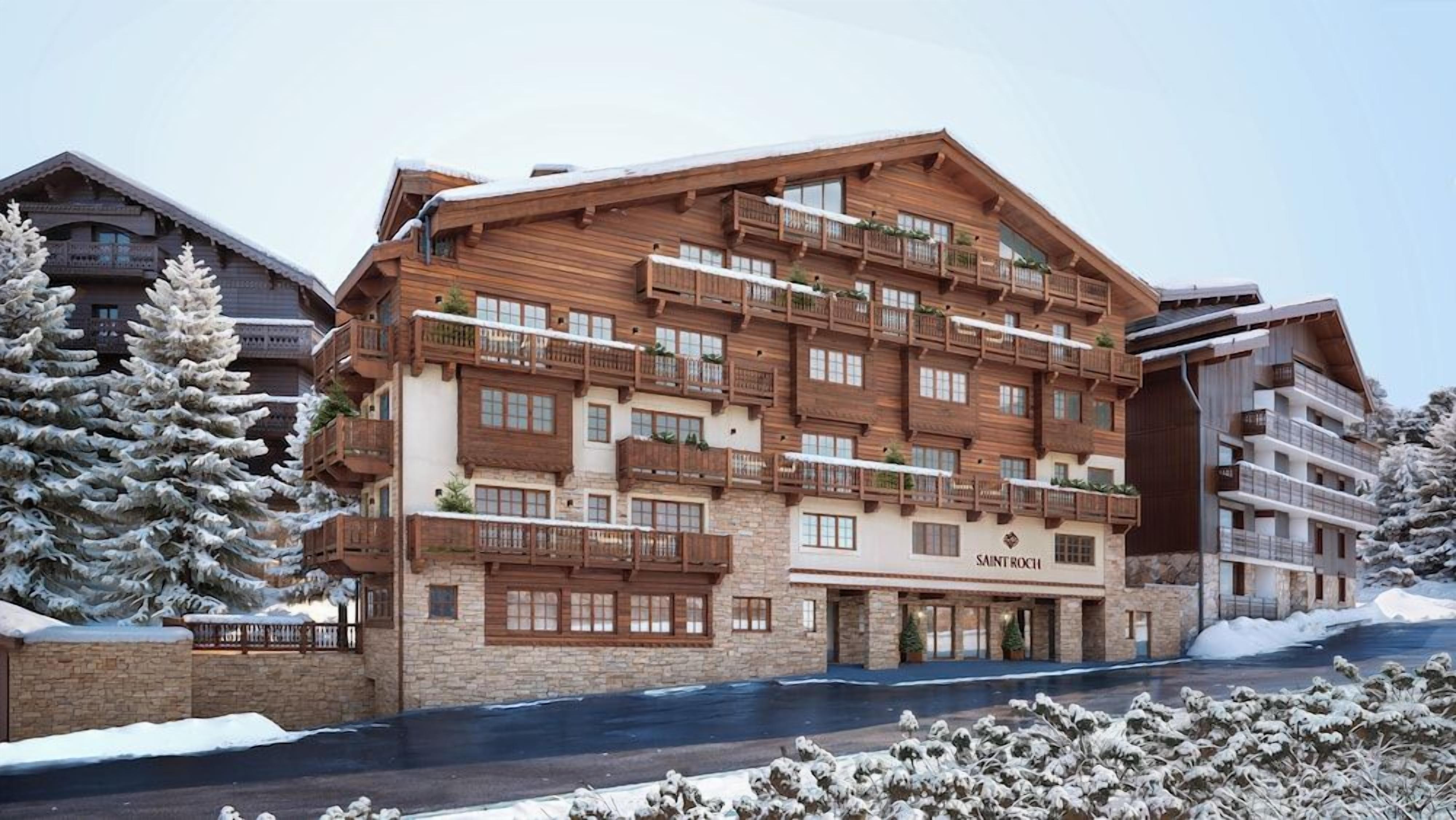 Un hôtel à plusieurs étages, doté de balcons, d’une façade en pierre et entouré d’un paysage enneigé.