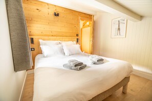 A bedroom with a wooden headboard, a bed with white linens, and two rolled towels on the bed. - The Black Stag: Finnish sauna, mountain view, sleeps 8 (La Bresse)