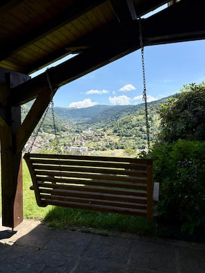 Eine hölzerne Bank unter einem Schutzdach mit Blick auf ein Tal und Berge.