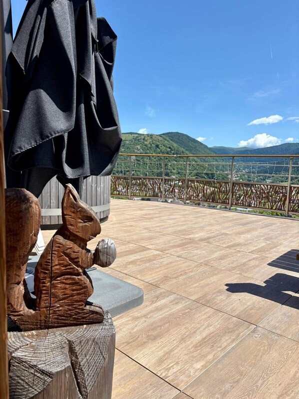 A wooden sculpture on a balcony with a view of a mountain and a clear sky.