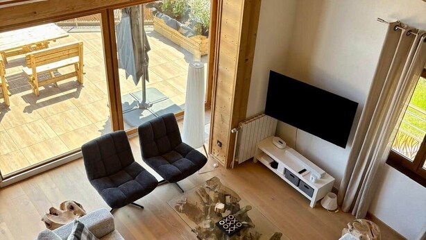 A spacious living room with a large window, two sofas, a coffee table, and a TV. - The Black Stag: Finnish sauna, mountain view, sleeps 8 (La Bresse)