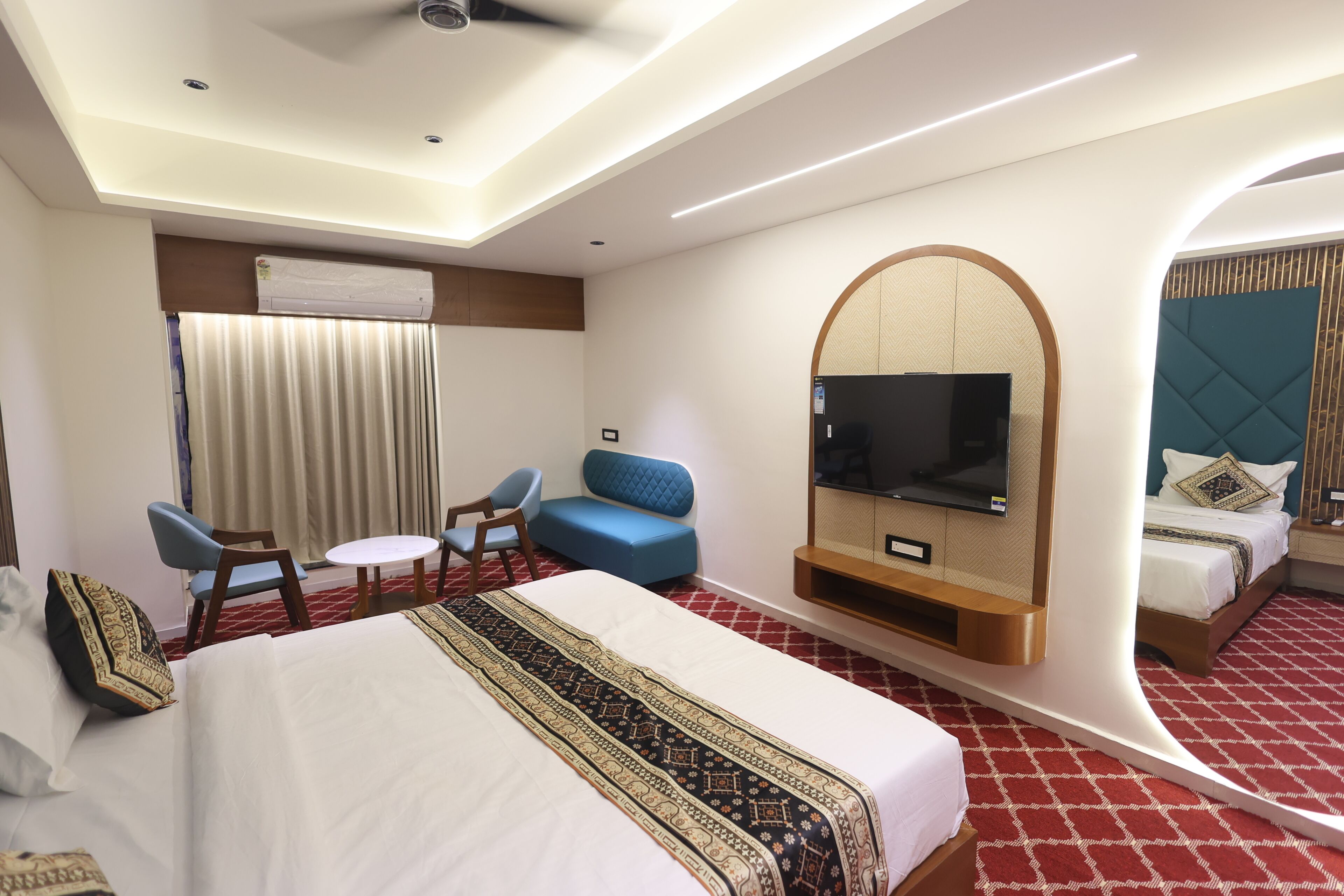 Habitación de hotel con una cama grande, televisión, sofá y espejo.