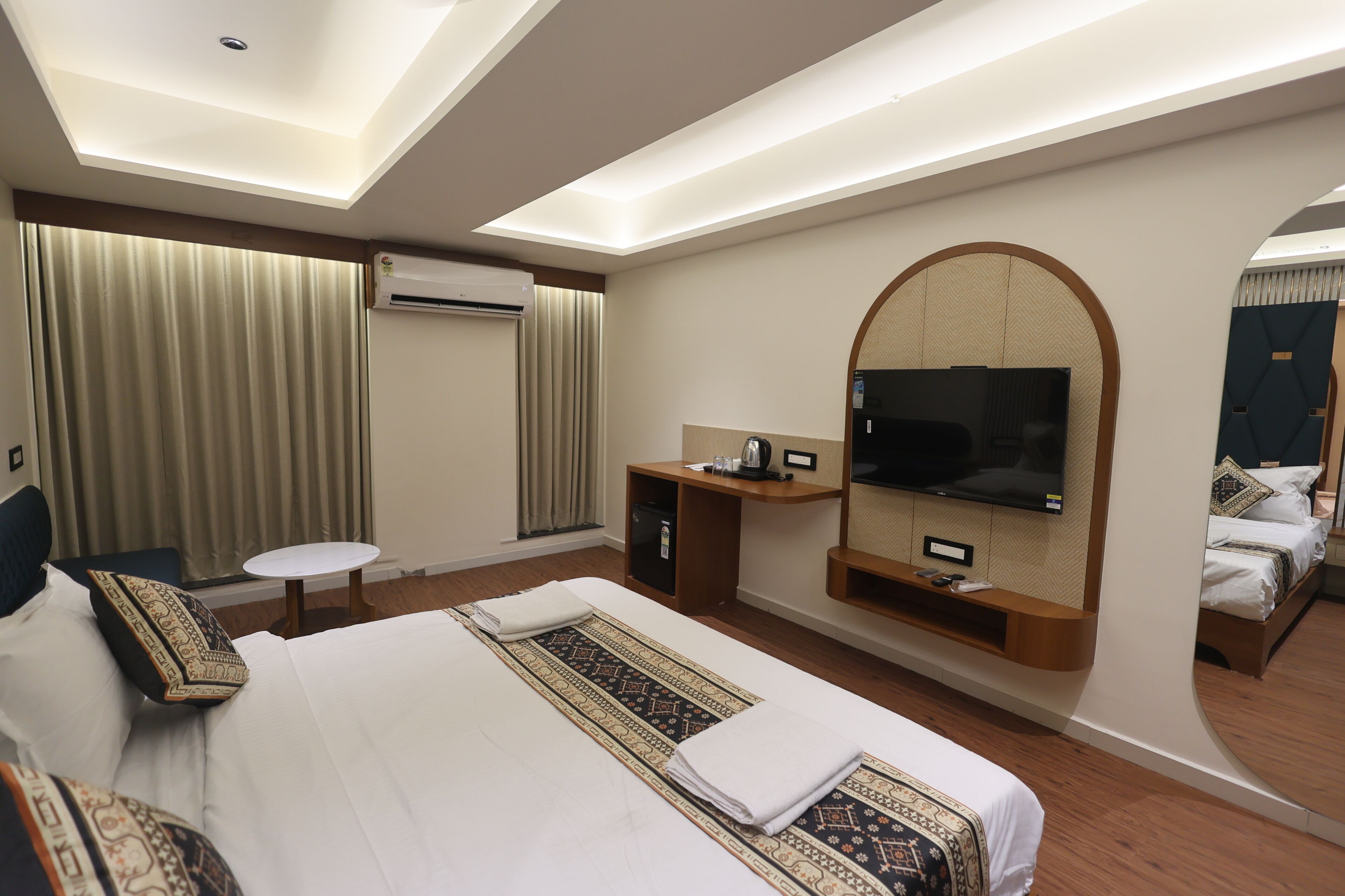 Habitación de hotel con una cama grande, televisor montado en la pared, escritorio con una silla y un equipo de aire acondicionado.