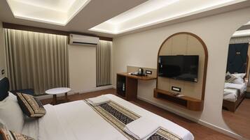 Habitación de hotel con una cama grande, televisor montado en la pared, escritorio con una silla y un equipo de aire acondicionado.