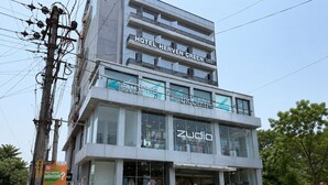 A multi-story building with a 'HOTEL HERVEN GREEN' sign, a 'STRUMUK UK CENTRE' store, and a 'ZUDIO' clothing store.