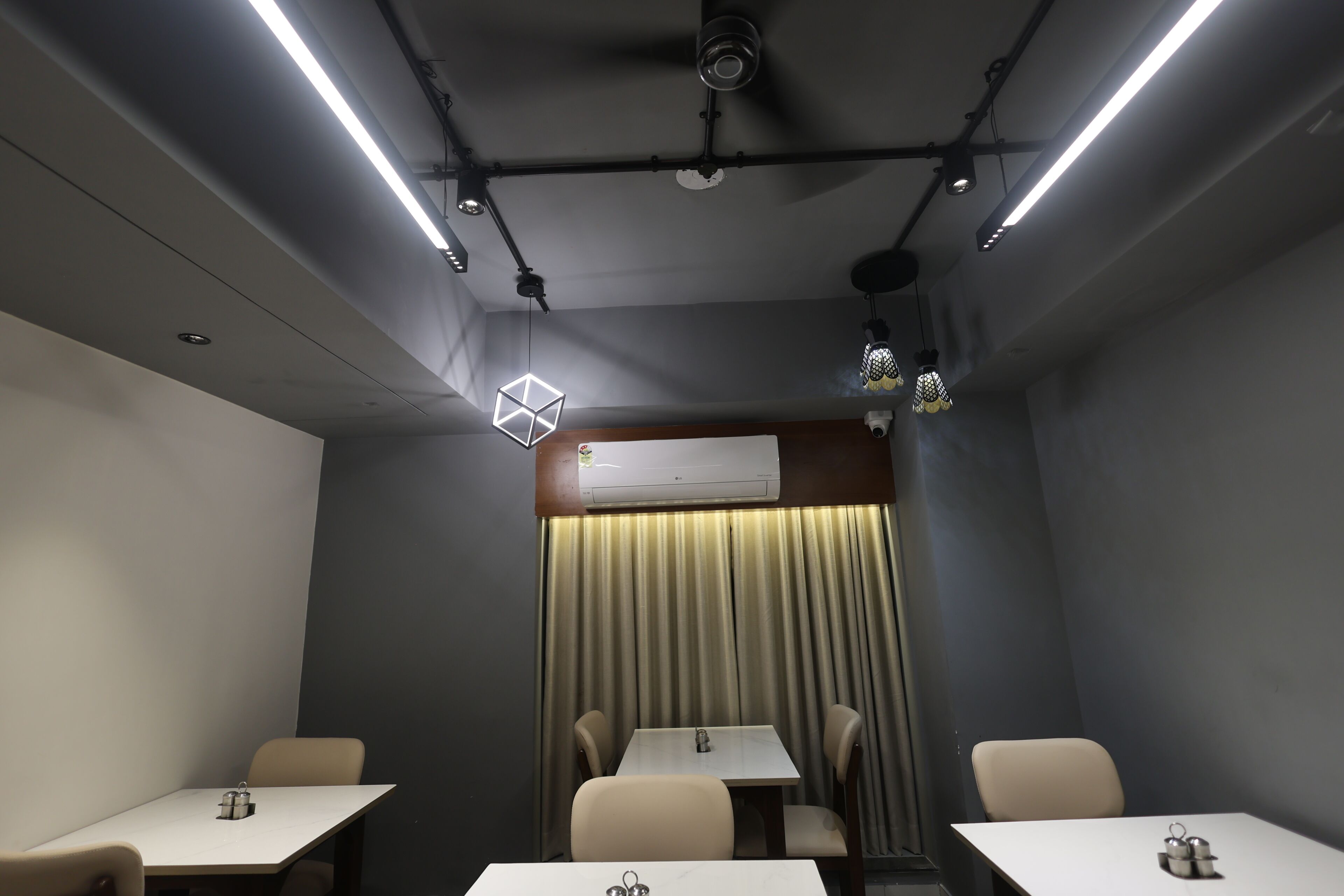 Un salón de conferencias con mesas, sillas e iluminación en el techo.