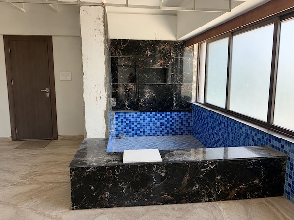 Une pièce avec un comptoir en marbre noir, des carreaux de mosaïque bleus, une porte et une fenêtre.