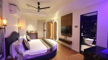 A modern bedroom with a curved bed, a ceiling fan, a TV, and a bathroom with a marble countertop.