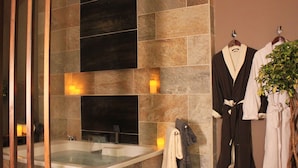 A modern bathroom with a freestanding bathtub, a towel rack with robes, and a potted plant. - Villa Buena Onda (PLAYAS DEL COCO)