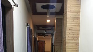 A hallway with a tiled floor, wooden paneling on one side, and a door at the end.