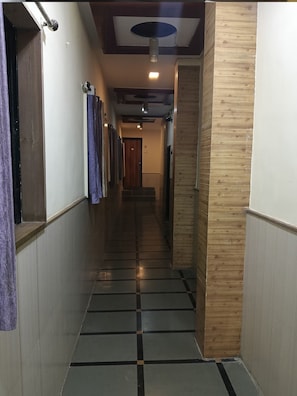 Un pasillo con suelo de baldosas, paneles de madera en una pared y una puerta al final.