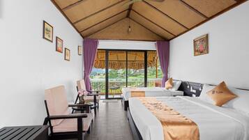 A hotel room with a bed, a chair, a table, and a view of a garden through a large window.