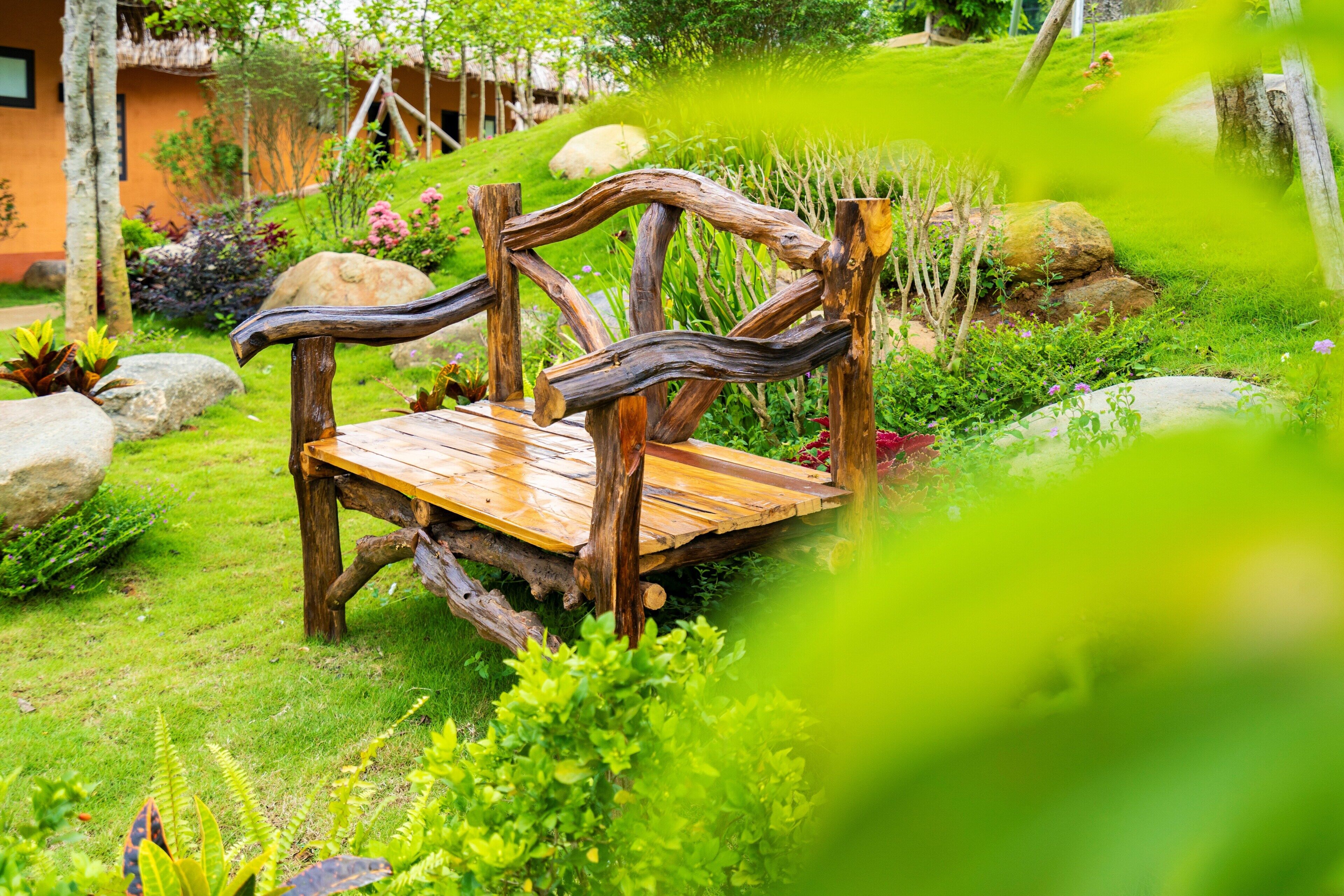 Un banco de madera en un jardín exuberante con rocas y plantas.