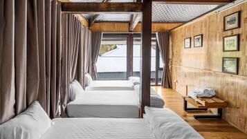 Habitación con tres camas, paredes de madera y un banco con toallas.