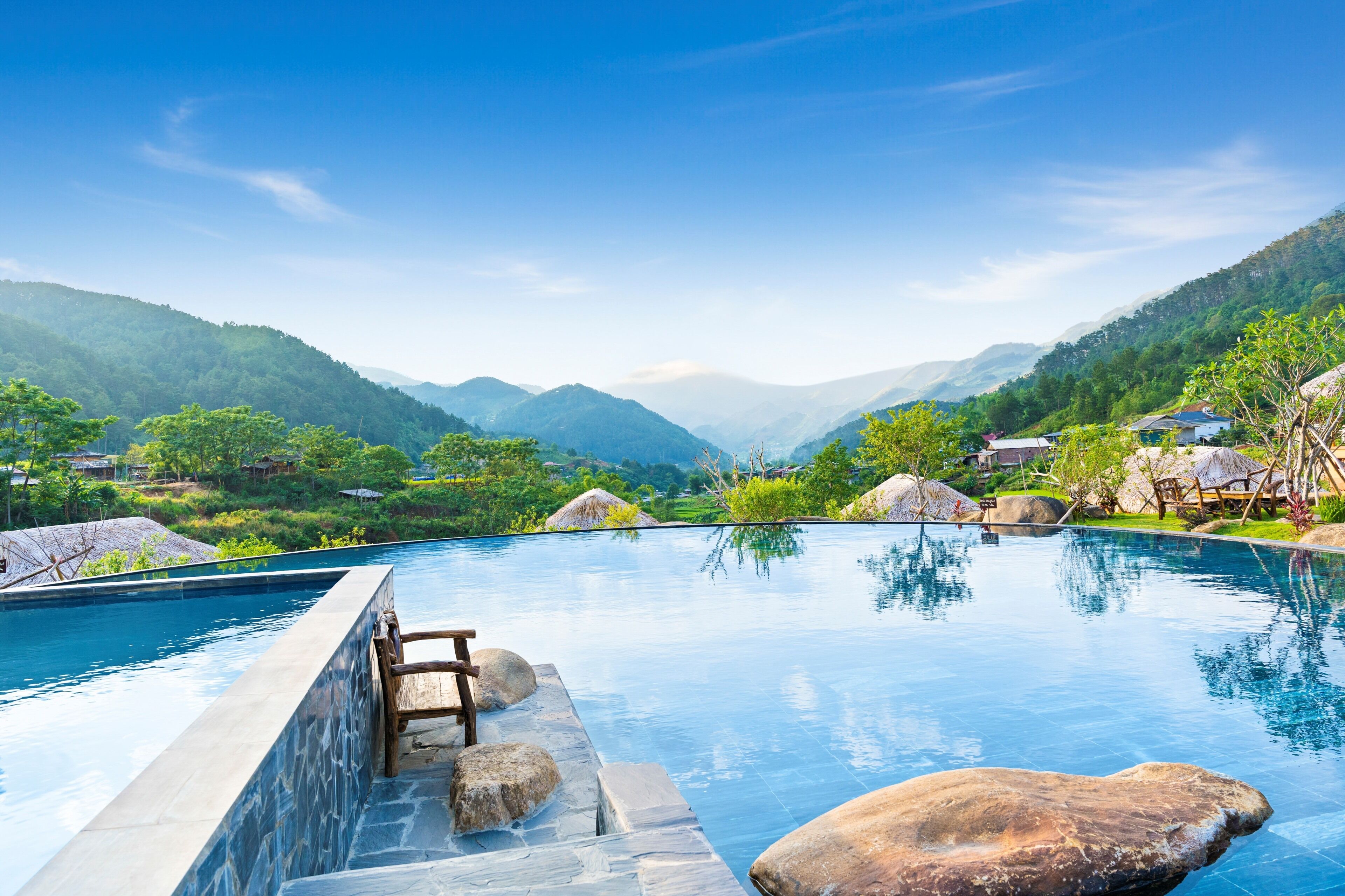 A pool with a stone edge, large rocks, and a wooden ladder.