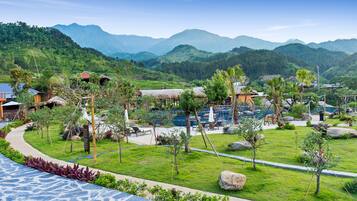 Un resort con piscina, edificios de techo de paja y exuberante vegetación.