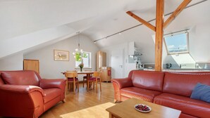 Un loft espacioso con comedor, dos sofás de cuero, una mesa de centro de madera y una cocina al fondo.