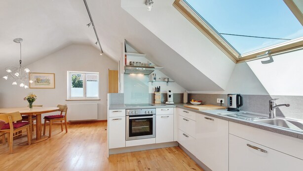 Una cocina moderna con tragaluces, suelo de madera y armarios blancos.