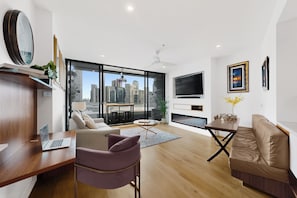 Uma sala de estar moderna com vista para a cidade, uma televisão de tela plana e um espaço de jantar.