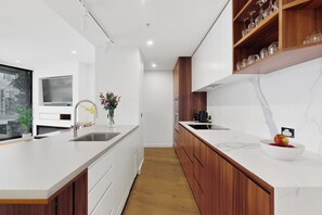 Una cocina moderna con una isla grande, armarios de madera, salpicadero de mármol y televisor integrado.