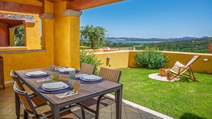 En udendørs terrasse med et spisebord, en stol og udsigt over landskabet.