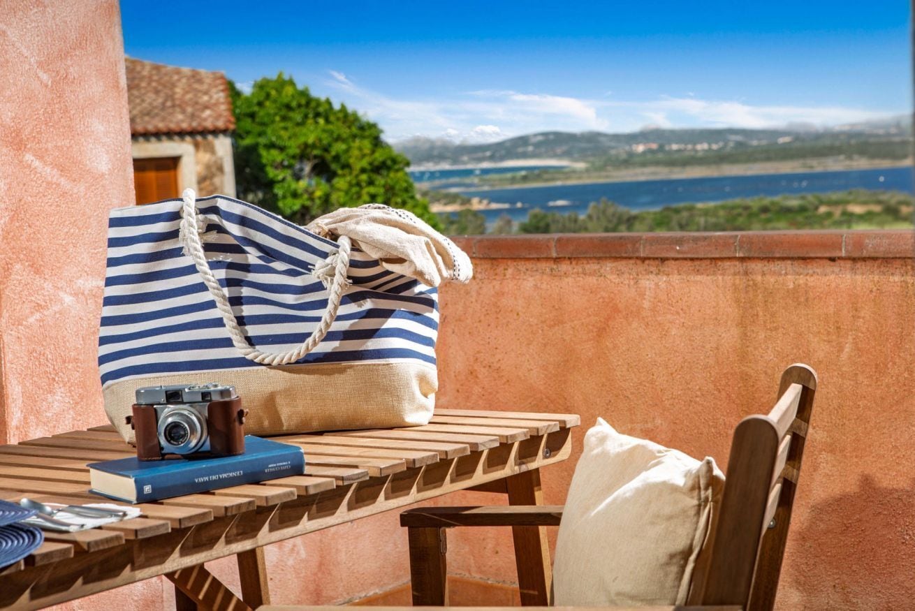 A wooden table with a striped bag, a camera, and a book.