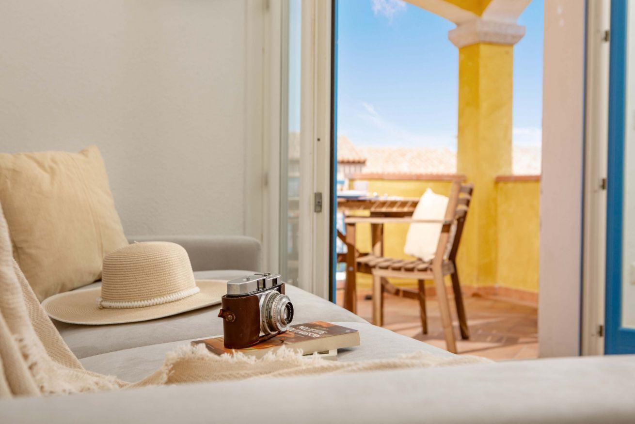 A room with a bed, a camera, a hat, and a book on a table.