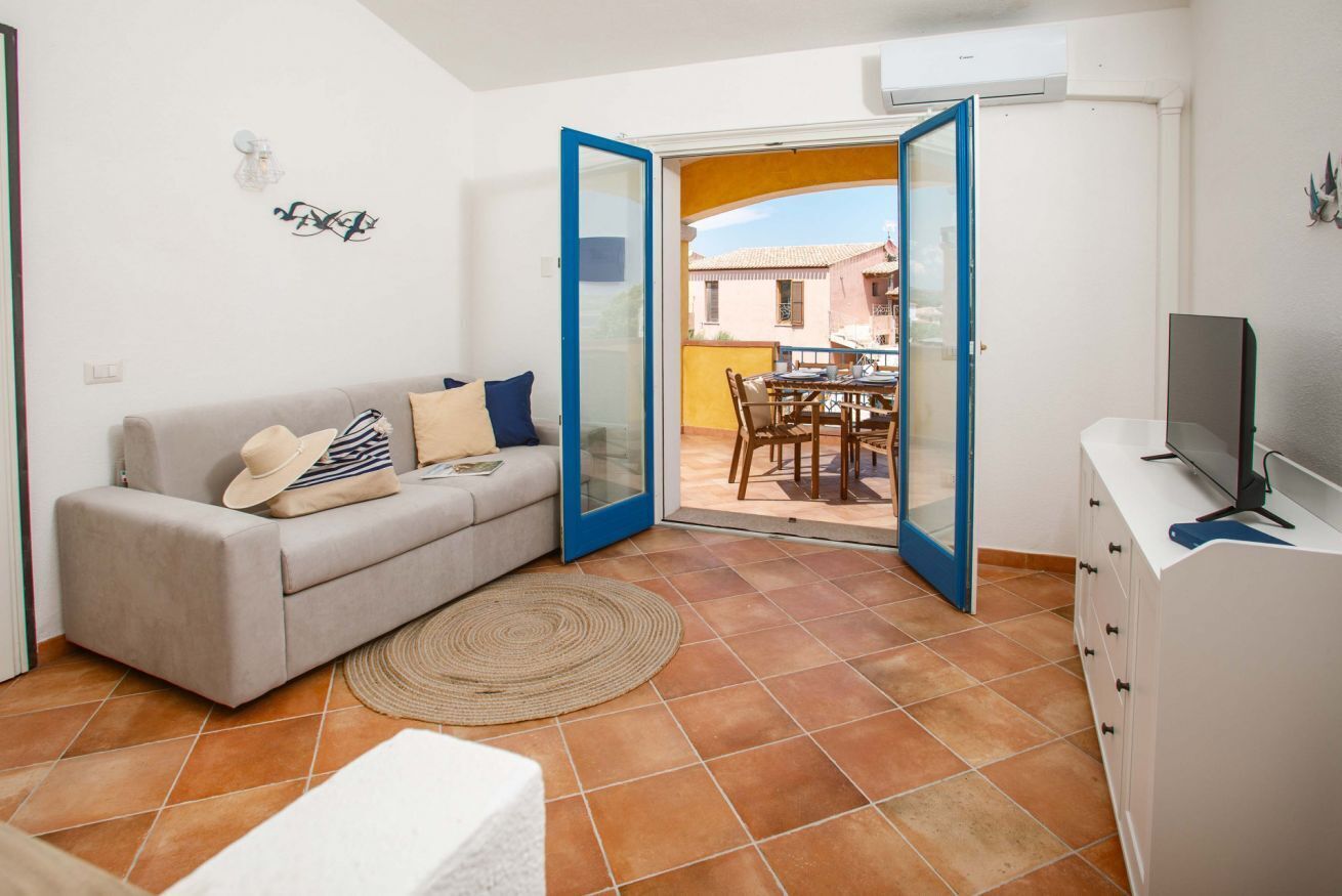 Un salon comprenant un canapé, un téléviseur, une table à manger et une porte-fenêtre coulissante donnant sur une terrasse extérieure.