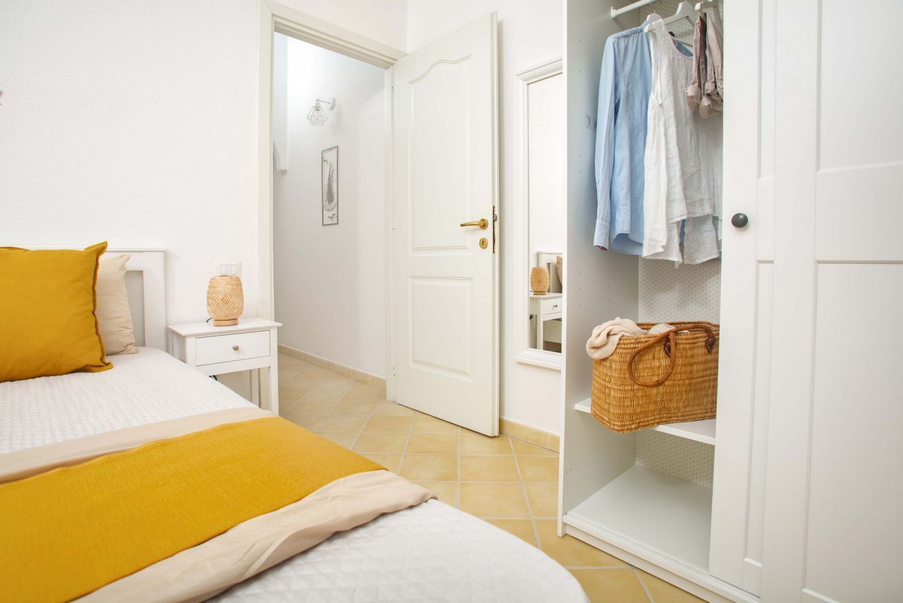 Una camera da letto con un letto, un comodino e un armadio pieno di vestiti.