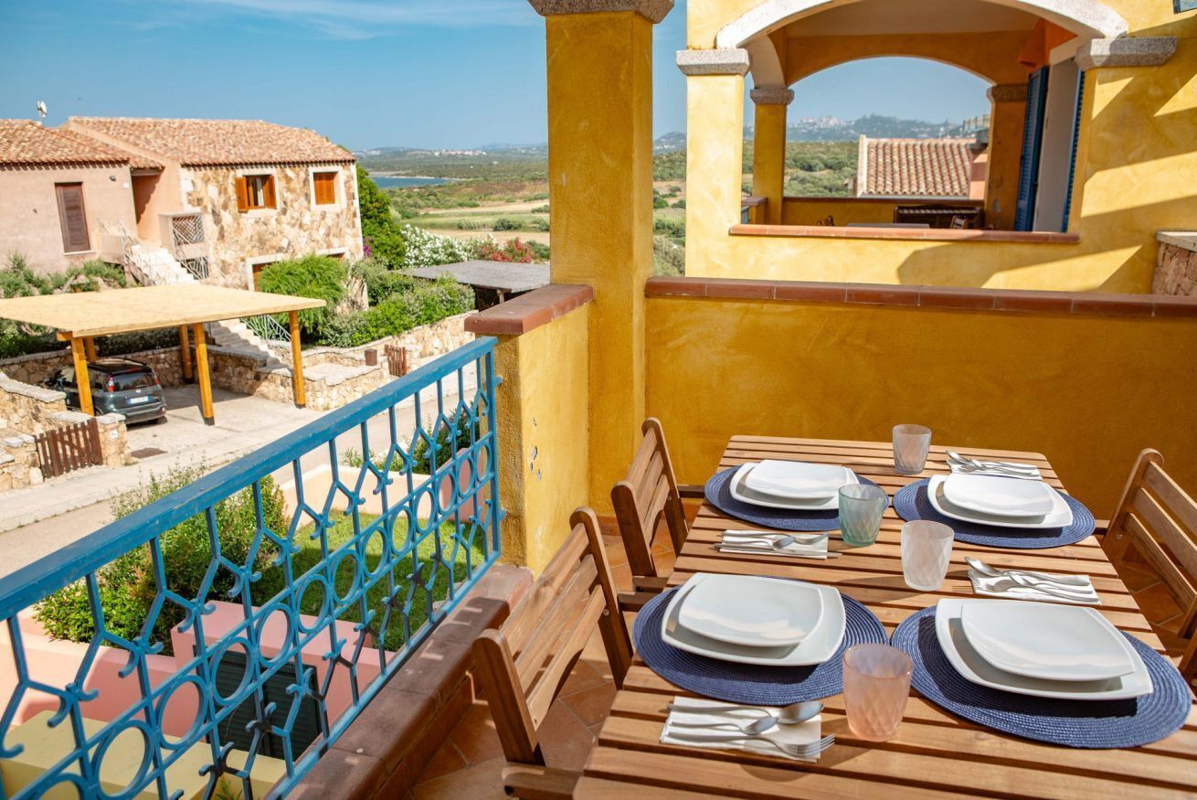 A balcony with a table set for dining, overlooking a rural landscape.
