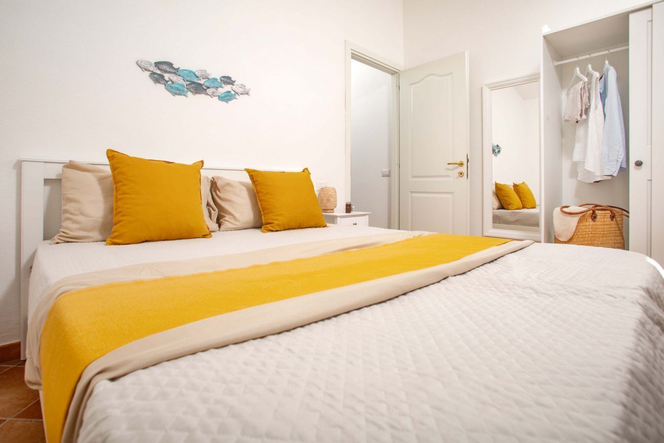 Een slaapkamer met een bed, nachtkastje, spiegel en kledingkast.