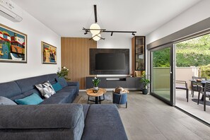 A modern living room with a sofa, TV, and a dining area with a table and chairs. - Alba Azzura 2-bedroom apartment in Zaton (Zaton)