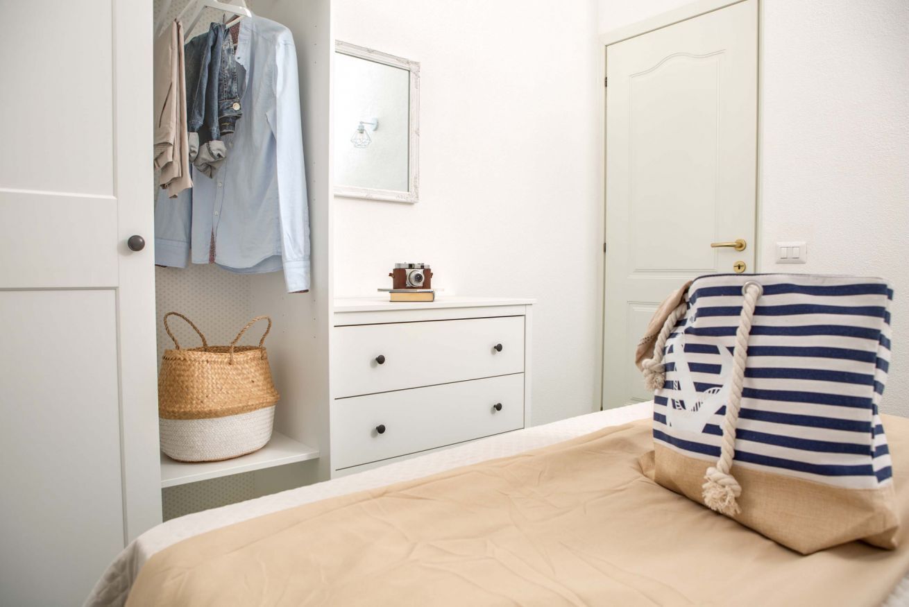 A bedroom with a bed, a dresser, a mirror, and a wardrobe.