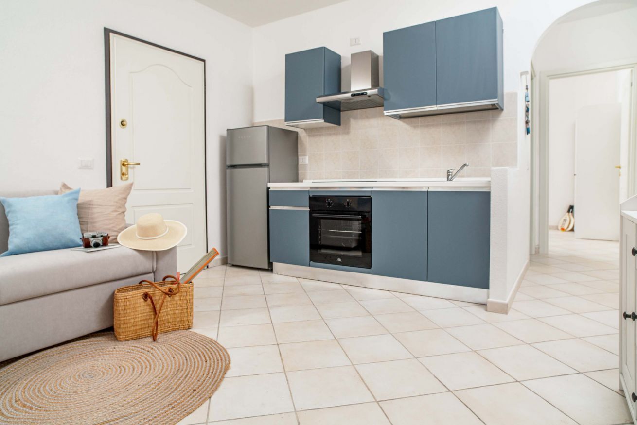 A compact kitchen with blue cabinets, a white countertop, and a built-in oven.