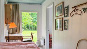 A bedroom with a large bed, a hanging lamp, a wicker basket, and framed pictures on the wall. - Colourful summer house on Bornholm (Hasle)