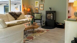A living room with a sofa, a wooden coffee table, a fireplace, and framed pictures on the wall. - Colourful summer house on Bornholm (Hasle)