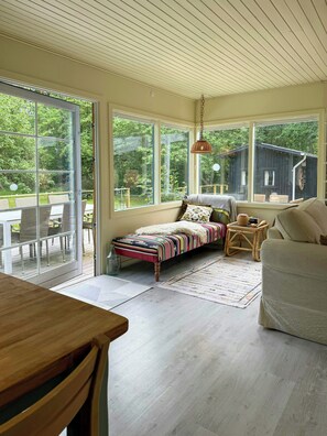 A cozy room with a bed, a chair, a table, and large windows. - Colourful summer house on Bornholm (Hasle)