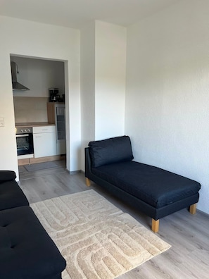 Ein gemütlicher Wohnbereich mit Sofa, Teppich, Küchenzeile und Essbereich.