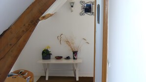 A room with a sloped ceiling, a white wall, a small table with a potted plant, a bowl, and a pair of shoes. - Bed and Breakfast 'La Rivetière - Chambre Les Rouges' with Shared Terrace, Shared Garden and Wi-Fi (Courcemont)