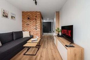 Ein modernes Wohnzimmer mit einer Ziegelfassade, einer Couch, einem Couchtisch, einem Fernseher und einer Fernbedienung.