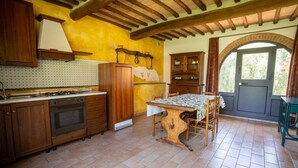 A kitchen with wooden cabinets, a stove, and a dining table with chairs. - Beautiful Home With Pool in Toskana (Siena)