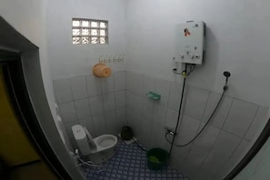 A small, tiled bathroom with a toilet, a shower, and a water heater. - Cozzy Villa Mutiara Putih Pangalengan (Pangalengan)