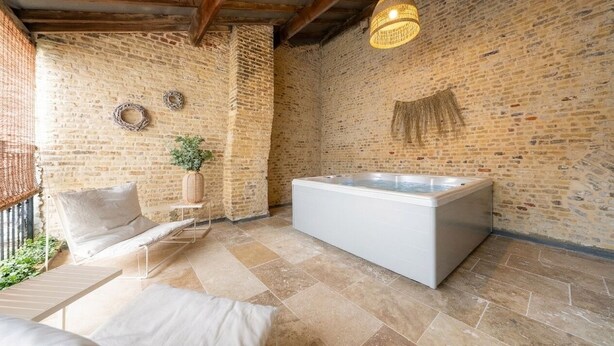 Ein Wellnessbereich mit Whirlpool, Korbstuhl und einer Pendelleuchte.
