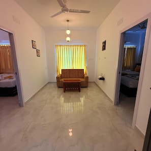 Uma sala de estar ampla com sofá, mesa de centro, ventilador de teto e janela com cortinas.