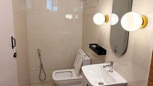 A modern bathroom with a shower, toilet, and sink.